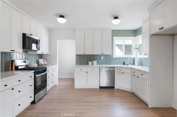 a kitchen with appliances a sink a window and cabinets
