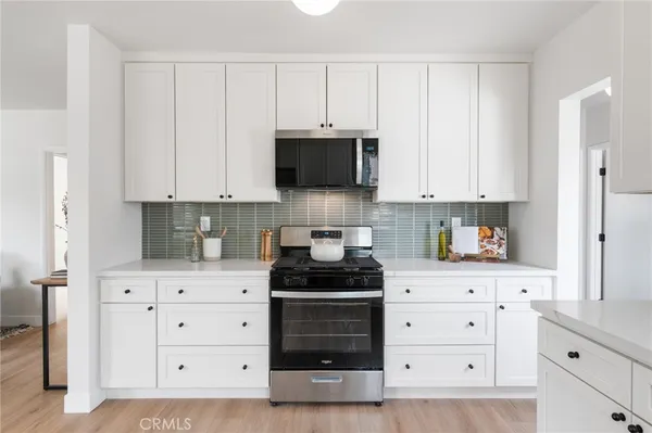 a kitchen with white cabinets and a window