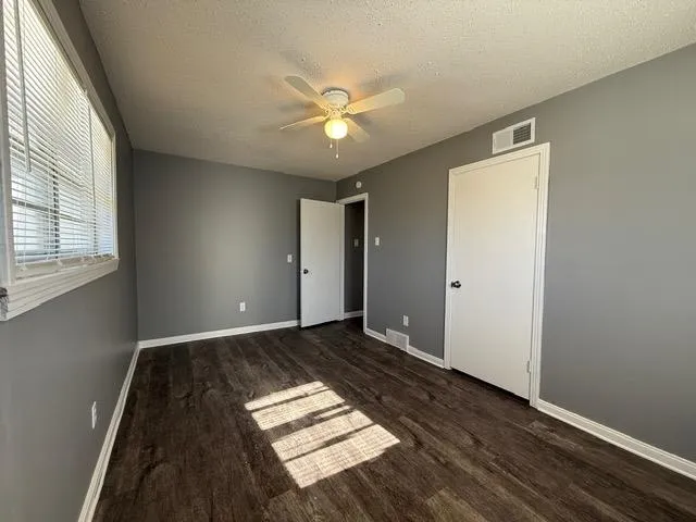 a view of an empty room with window and wooden floor