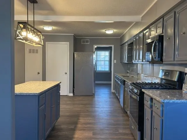 a kitchen with stainless steel appliances granite countertop wooden floors and granite counter tops