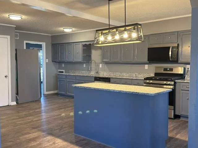 a kitchen with kitchen island granite countertop a sink cabinets and stainless steel appliances