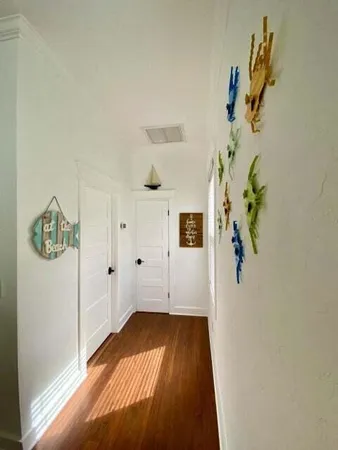 a view of a hallway with wooden floor and cabinet