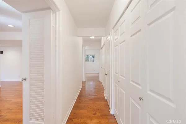 a view of a hallway with wooden floor and a bathroom