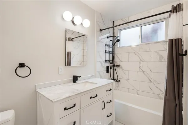 a bathroom with a granite countertop sink a mirror and a bathtub