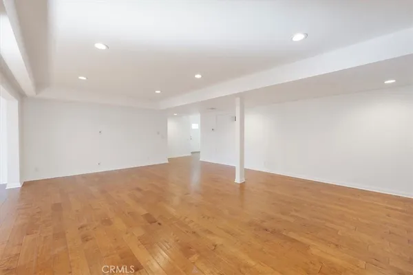 an empty room with wooden floor and natural light