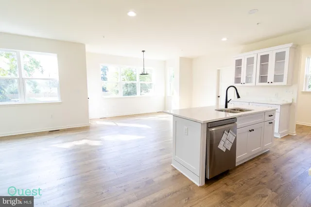 a view of a living room with wooden floor and white walls