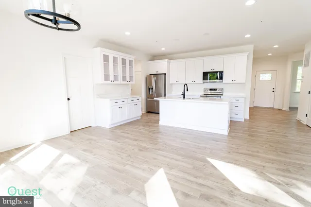 a kitchen with stainless steel appliances a refrigerator sink and white cabinets
