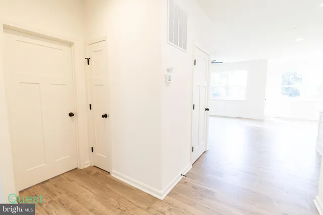 a view of a kitchen and an empty room with wooden floor and a window