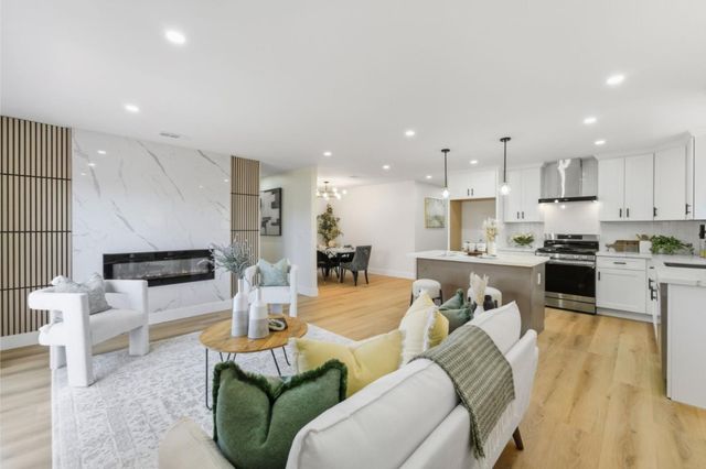 a living room with furniture wooden floor and kitchen view