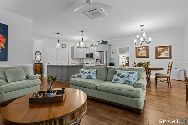 a living room with furniture kitchen view and a chandelier
