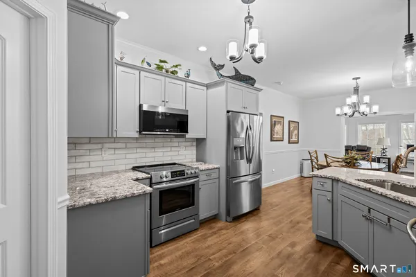 a kitchen with stainless steel appliances granite countertop a refrigerator a stove a sink dishwasher a dining table and chairs with wooden floor