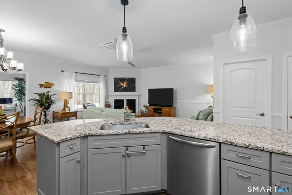 a kitchen with granite countertop cabinets a sink dishwasher a dining table and chairs with wooden floor