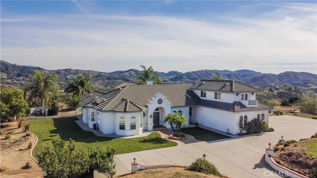 a front view of a house with a yard and mountain view in back