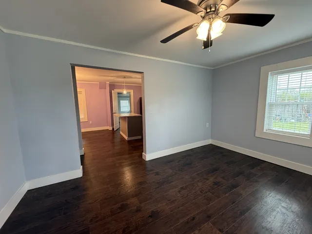a view of an empty room with wooden floor and a window