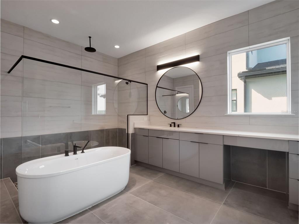 16808 Bolsena Drive Montverde, FL 34756 - Photo 39 of 68 a white bath tub sitting next to a bathroom sink and a mirror