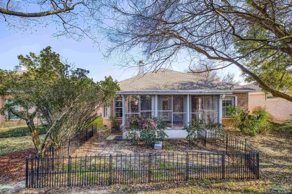 front view of a house with potted plants and a large tree
