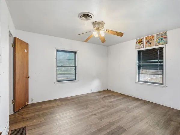 a view of an empty room with a window and wooden floor