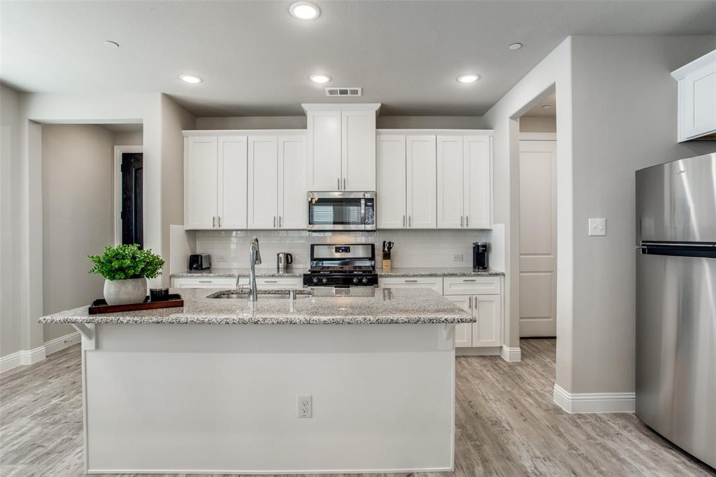 1718 Lisa Court Allen, TX 75002 - Photo 15 of 26 a kitchen with stainless steel appliances kitchen island granite countertop a refrigerator a stove a sink and white cabinets with wooden floor