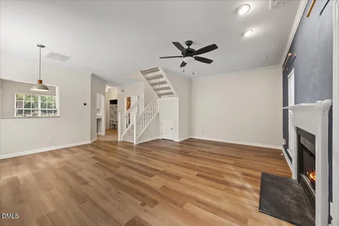a view of an empty room with wooden floor and a fireplace