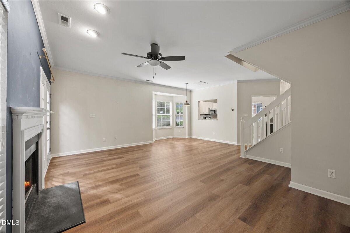 4329 Pine Springs Court Raleigh, NC 27613 - Photo 14 of 35 a view of an empty room with wooden floor and a fireplace