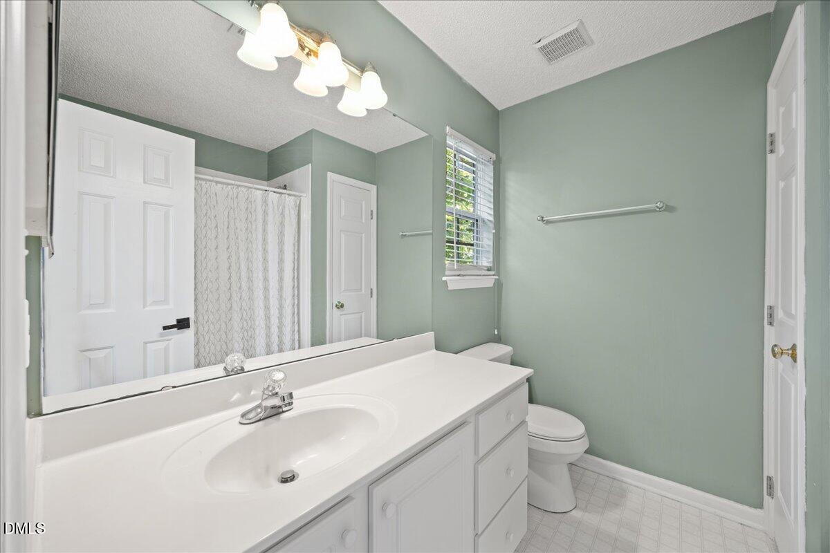 4329 Pine Springs Court Raleigh, NC 27613 - Photo 27 of 35 a bathroom with a sink a toilet and a mirror