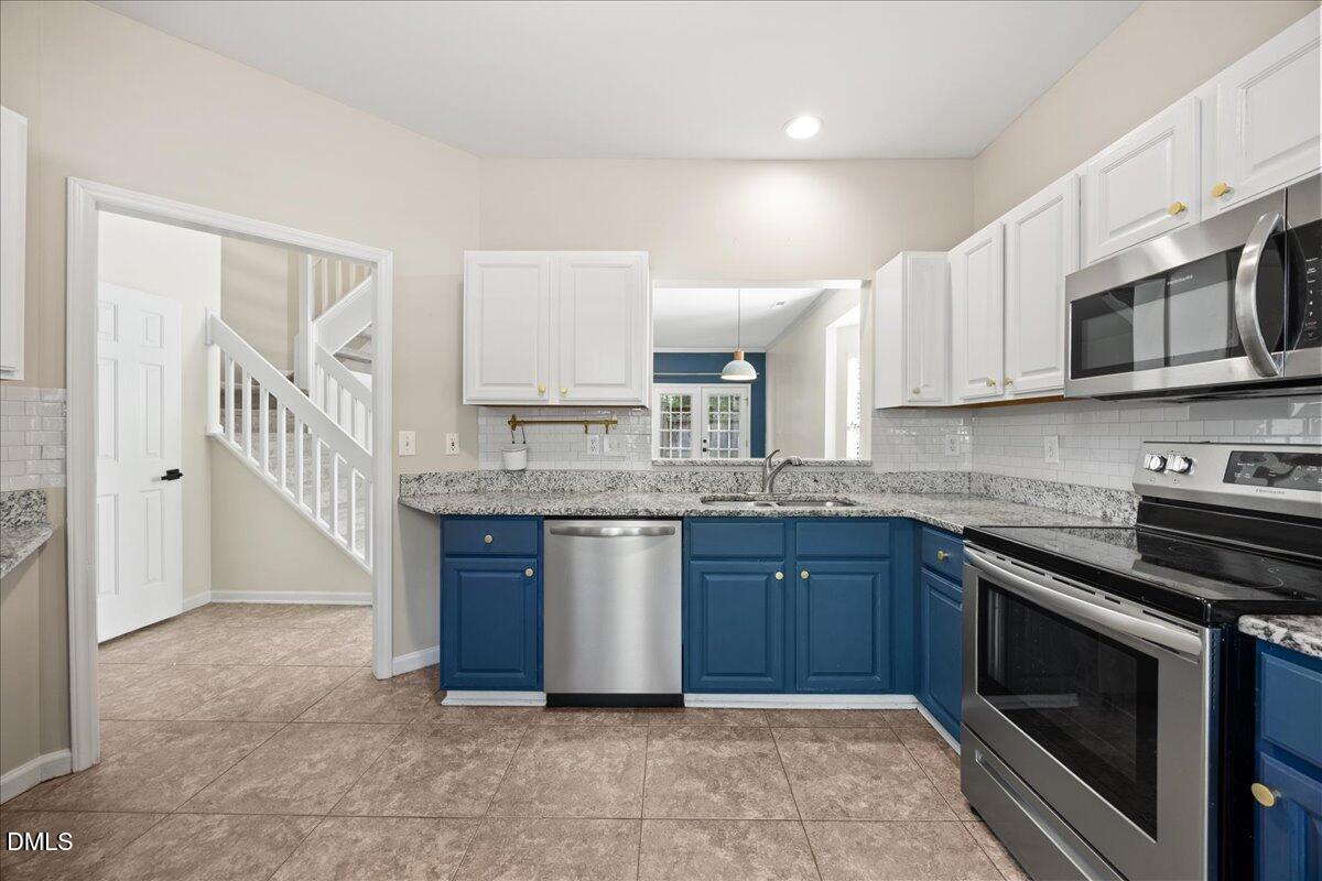 4329 Pine Springs Court Raleigh, NC 27613 - Photo 6 of 35 a kitchen with stainless steel appliances granite countertop a stove a sink and a microwave