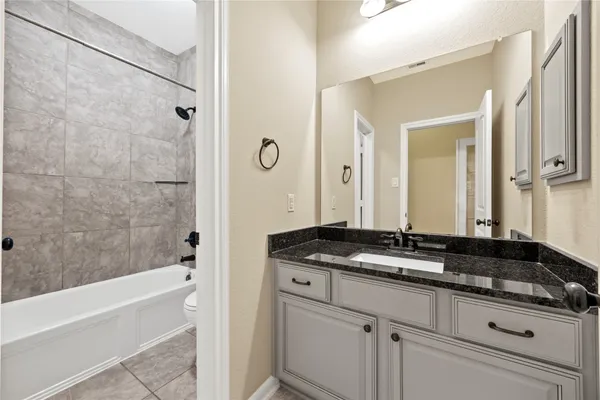 a bathroom with a granite countertop sink a mirror a bathtub and shower