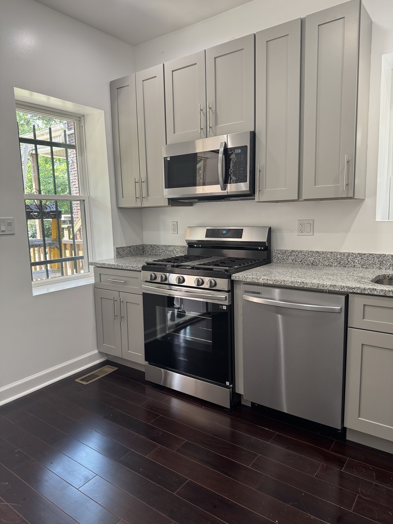 7204 South Union Avenue Chicago, IL 60621 - Photo 5 of 12 a kitchen with granite countertop a stove a sink and a microwave