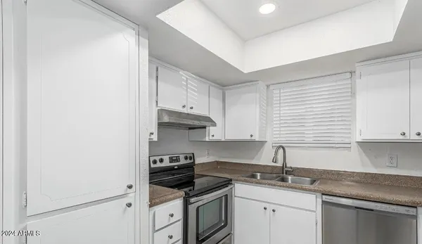 a kitchen with stainless steel appliances granite countertop white cabinets sink and stove
