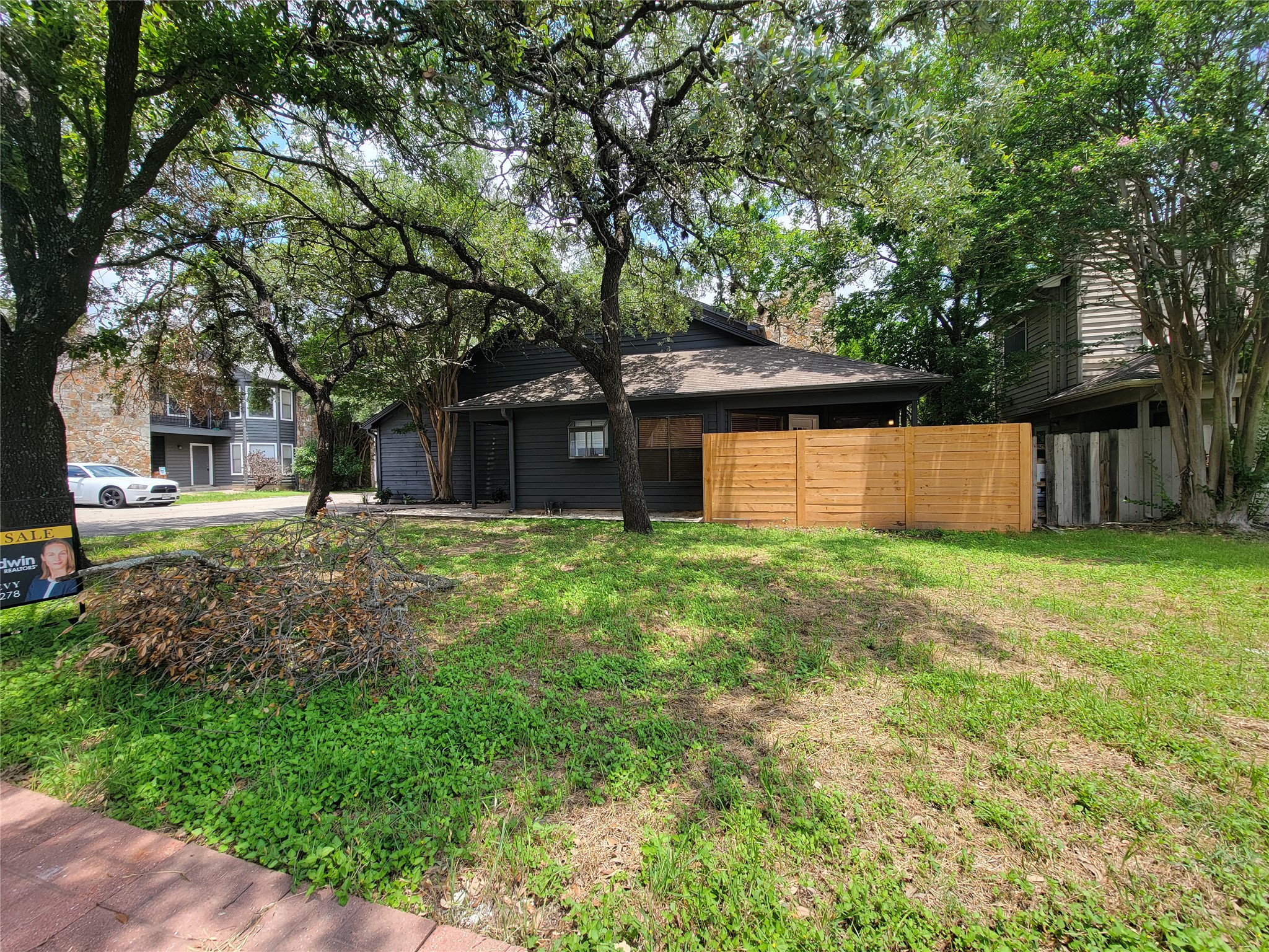 8706 Schick Road, Unit A Austin, TX 78729 - Photo 2 of 33 Mature trees shade this inviting front yard, showcasing a private wooden fence.