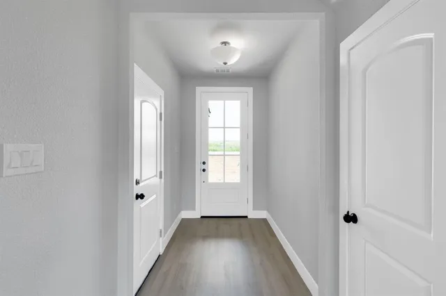 a view of a hallway with wooden floor and a window