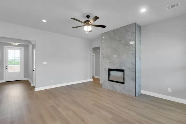 an empty room with wooden floor and a ceiling fan
