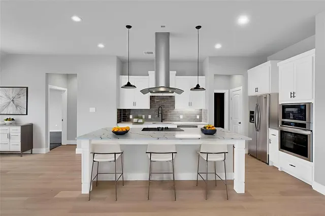 a kitchen with stainless steel appliances kitchen island granite countertop a stove a refrigerator and a stove top oven