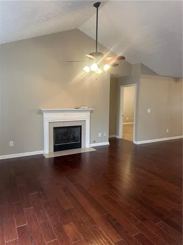 a view of an empty room with wooden floor fireplace and a window