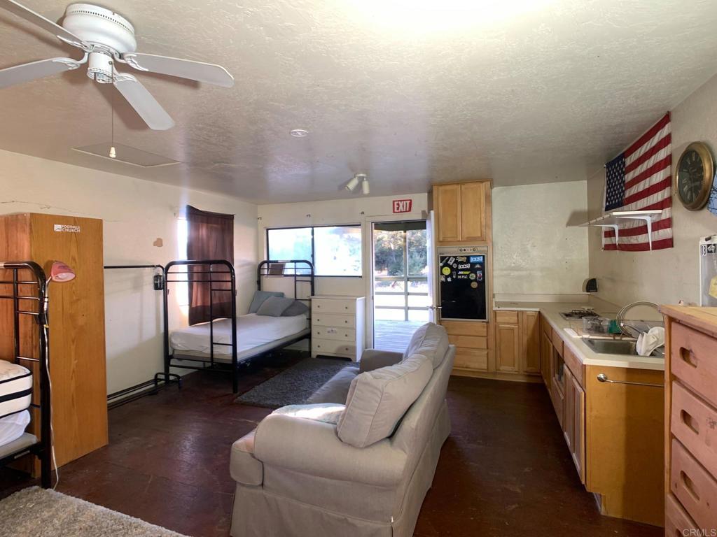 24352 Featherstone Canyon Road Lakeside, CA 92040 - Photo 19 of 68 a kitchen with stainless steel appliances kitchen island granite countertop a refrigerator a sink dishwasher a dining table and chairs with wooden floor