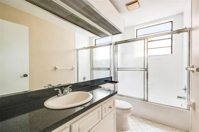 a bathroom with a granite countertop sink toilet a mirror and shower