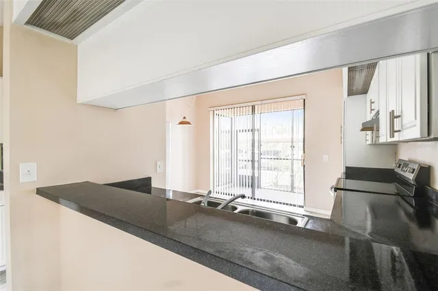 a view of a kitchen with granite countertop a sink and a refrigerator
