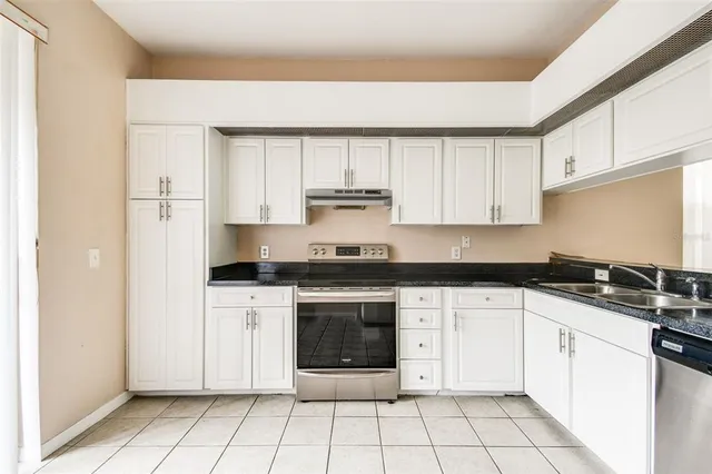 a kitchen with granite countertop a stove sink and cabinets