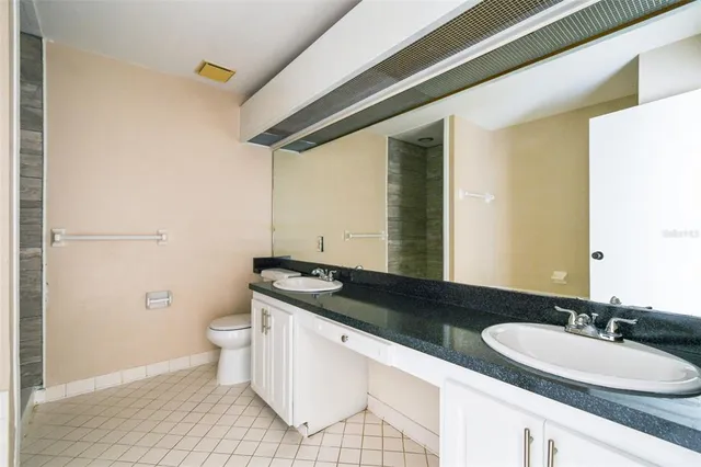 a bathroom with a granite countertop sink a toilet and a mirror