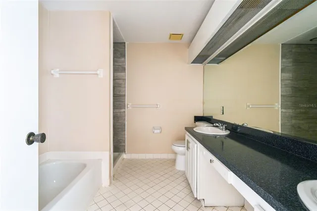 a spacious bathroom with a granite countertop sink a toilet a bathtub and shower