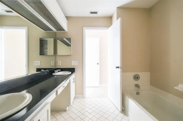 a spacious bathroom with a granite countertop sink and a bathtub