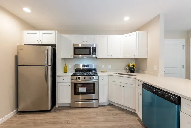 a kitchen with a refrigerator stove and white cabinets