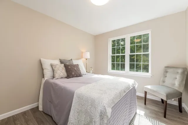 a bedroom with a bed a chair and next to a window