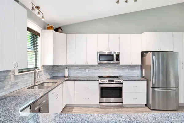a kitchen with granite countertop a sink stove and refrigerator