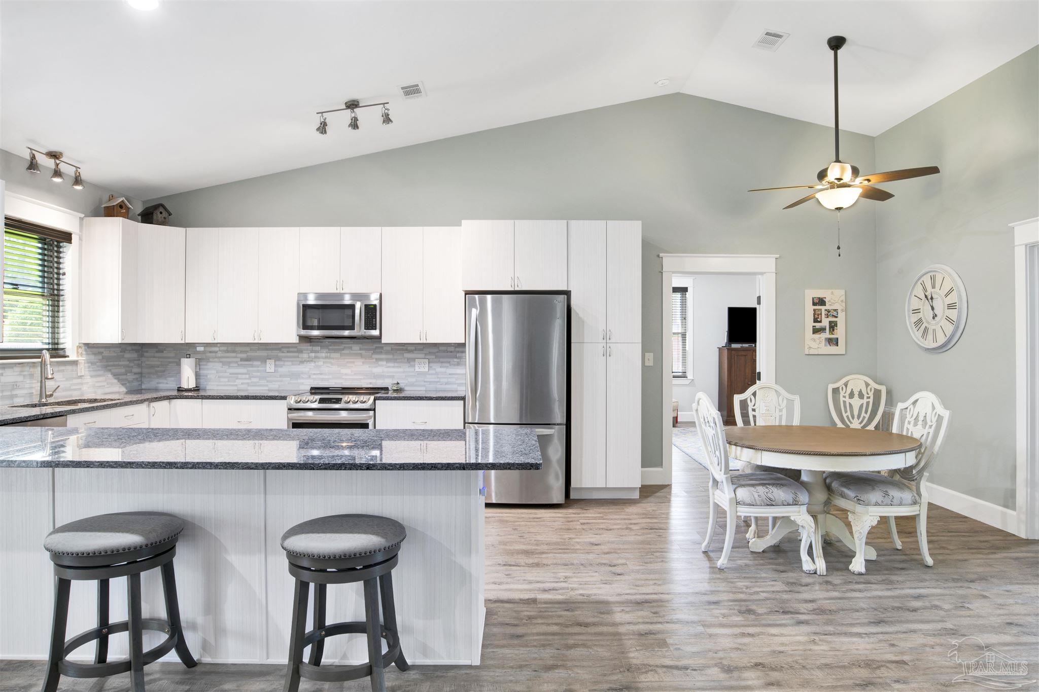2549 Santa Rosa Drive Lillian, AL 36549 - Photo 13 of 53 a kitchen with stainless steel appliances granite countertop a dining table chairs refrigerator and cabinets