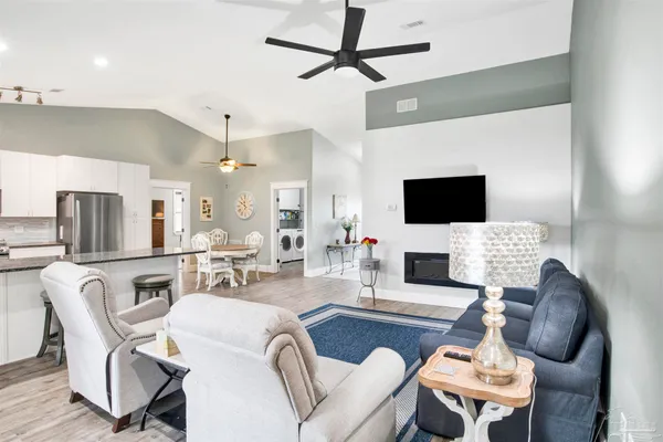 a living room with furniture a flat screen tv and kitchen view