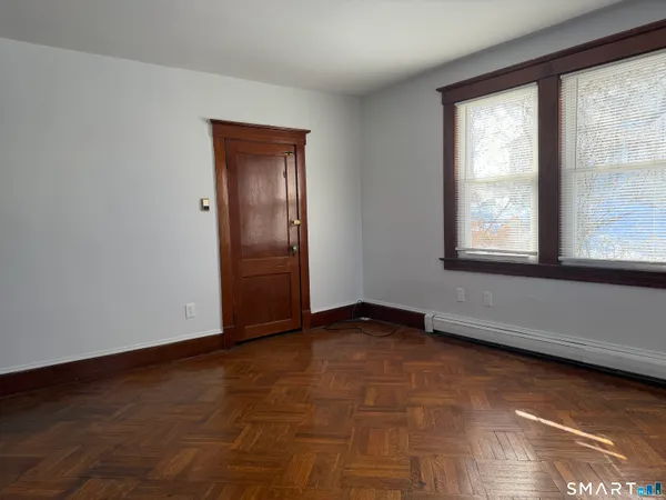 a view of an empty room with wooden floor and a window