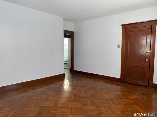 a view of an empty room with closet and wooden floor