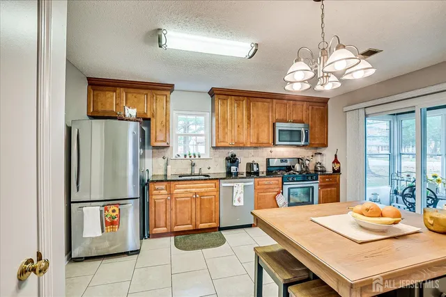 a kitchen with granite countertop stainless steel appliances a sink stove and refrigerator