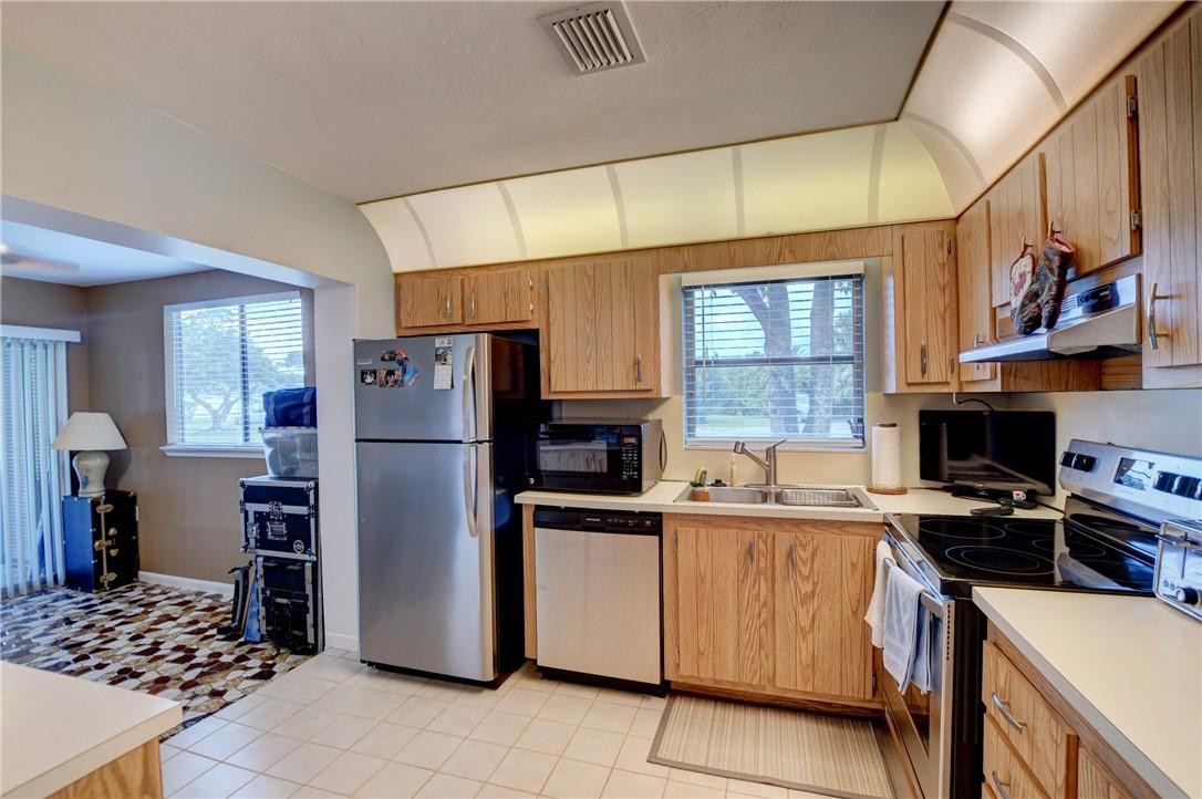 9285 Southwest 5th Street, Unit C Boca Raton, FL 33428 - Photo 20 of 31 a kitchen with stainless steel appliances a refrigerator a sink a stove a washer dryer and cabinets